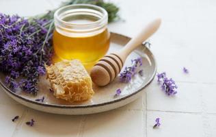 jarra com mel e flores frescas de lavanda foto