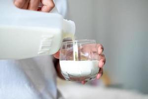 mulher derramando leite branco em um copo, comida de medicina de cuidados de saúde da vida diária foto