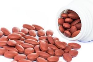 pílulas vermelhas derramando fora de um frasco de medicamento