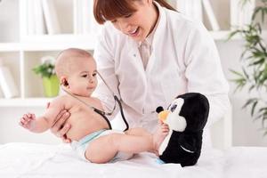sorrindo médico pediatra brincando e aproveite com paciente bebê foto