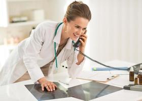 mulher feliz médico com fluorografia falando telefone