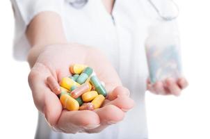 closeup com mão de uma mulher segurando vitaminas e comprimidos naturais