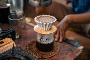 café por gotejamento, barista derramando água no café moído com filtro foto