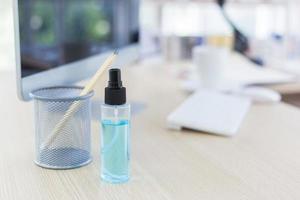 spray de álcool desinfetante na mesa do escritório em casa com um fundo desfocado. foto