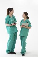 dois trabalhadores de saúde do sexo feminino vestindo uniforme e estetoscópio.
