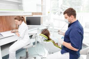 dentista jovem qualificado está curando os dentes femininos foto