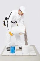 trabalhador misturar azulejo adesivo balde de água azulejos brancos foto