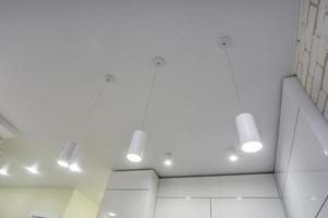 lâmpadas de halogênio no teto suspenso e construção de drywall em sala vazia em apartamento ou casa. tecto falso branco e forma complexa. foto