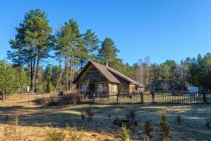 antiga casa de campo de madeira na aldeia do interior russo ao amanhecer na floresta de pinheiros. turismo ecológico e recreação foto