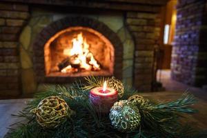 bolas de velas de natal e ramos de abeto em uma mesa de madeira perto da lareira. Humor festivo foto