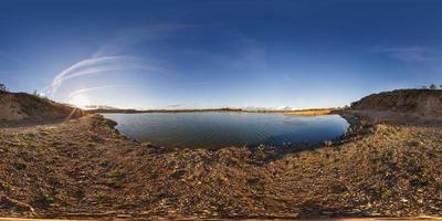 panorama completo sem costura 360 vista de ângulo perto da pedreira inundada com água para mineração de extração de areia ao sol da tarde em projeção equidistante esférica equirretangular para conteúdo vr ar foto