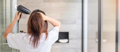 jovem usando secador de cabelo em casa ou hotel. penteados e conceitos de estilo de vida foto