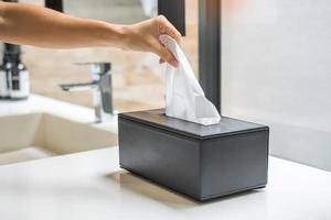 mão puxando papel higiênico no banheiro. conceito de limpeza, estilo de vida e higiene pessoal foto
