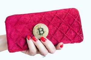 dinheiro virtual bitcoin dourado na bolsa de tecido feminino rosa. dedos com unhas vermelhas em uma moeda isolada no fundo branco foto