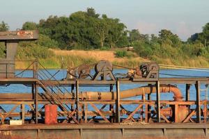 as embarcações de sucção de areia estão transportando areia de tubos de aço em rios profundos para a construção de indústrias como casas, prédios, estradas e muitas outras onde a areia é usada como mistura. foto