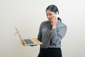 Mulher de negócios asiáticos falando ao telefone com a mão segurando um laptop foto