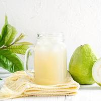 deliciosa goiaba com suco fresco em fundo de mesa de madeira branca. foto