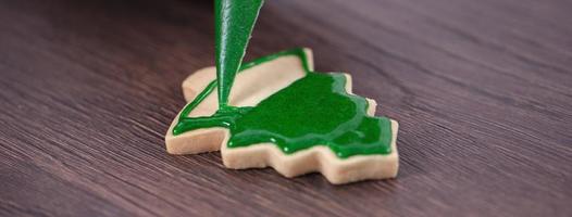 close-up de desenho de biscoito de açúcar de árvore de natal no fundo da mesa de madeira com glacê. foto