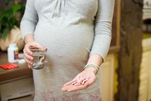 jovem mulher grávida bonita tomando pílulas, vitaminas, medicamentos