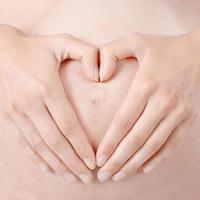 mulher grávida coração forma inscreva se símbolo mãos no estômago foto