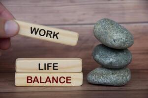 texto de equilíbrio de vida de trabalho em blocos de madeira com pedras e fundo de capa de madeira. foto