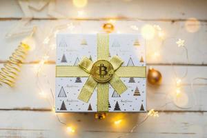 uma moeda bitcoin em uma caixa com um presente para o natal e ano novo. criptomoeda, finanças, riqueza e investimento. luzes de fadas, cartão foto