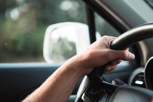 a mão do motorista no volante do carro. condução, regras de trânsito, segurança ao volante. foto