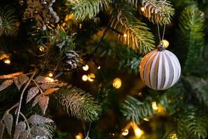 árvore de ano novo decorada de natal clássica. árvore de natal com enfeites de wite e prata, enfeites de brinquedo e bola. apartamento de design de interiores de estilo clássico moderno. véspera de natal em casa. foto