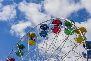 roda gigante colorida contra o céu azul com nuvens foto