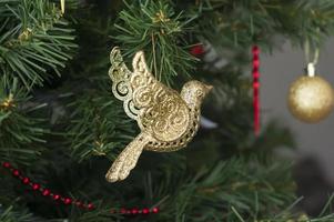 close-up de brinquedo de pássaro dourado para árvore de natal. fundo festivo foto