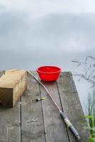 equipamento de pescador em uma ponte de madeira no fundo de um rio. vara de pescar no cais foto