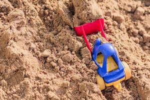 pequeno escavador de brinquedo trabalhando na pedreira de areia, conceito de construção foto