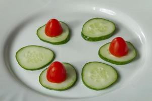 pepinos e tomates cereja em um prato branco foto