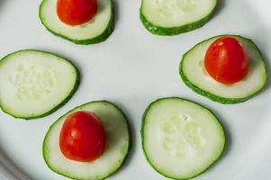 pepinos e tomates cereja em um prato branco foto