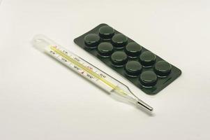 pílulas de remédio e termômetro em fundo branco foto