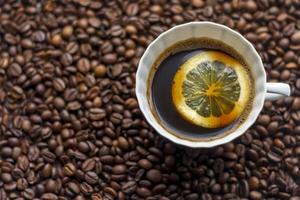 xícara de café com limão no fundo de grãos de café foto