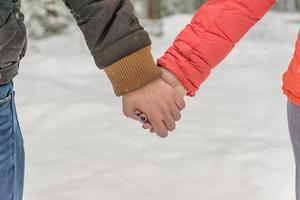homem e mulher de mãos dadas. jovem casal caminhando em winter park foto