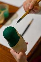 menina pintar boneca russa chamada matrioshka com tinta verde foto