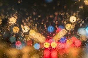 estrada desfocada com luzes pela janela do carro molhado