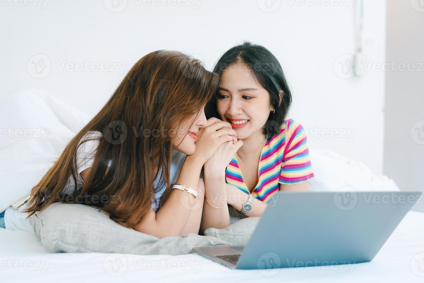 lgbtq, lgbt-konzept, homosexualität, porträt von zwei asiatischen frauen, die glücklich zusammen posieren und sich lieben, während sie computer-laptop auf dem bett spielen foto