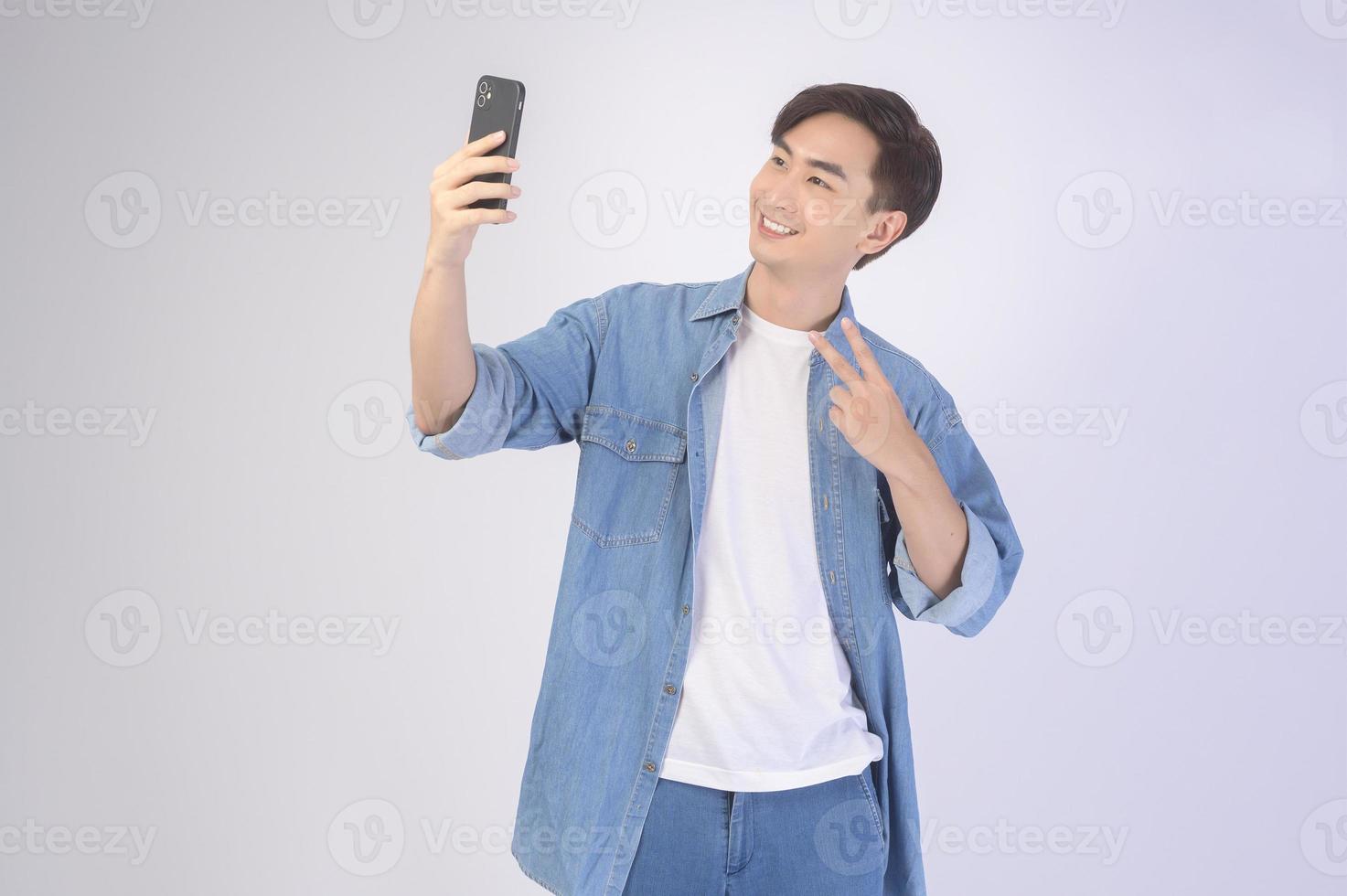 junger asiatischer Mann mit Smartphone auf weißem Hintergrund, Technologiekonzept. foto