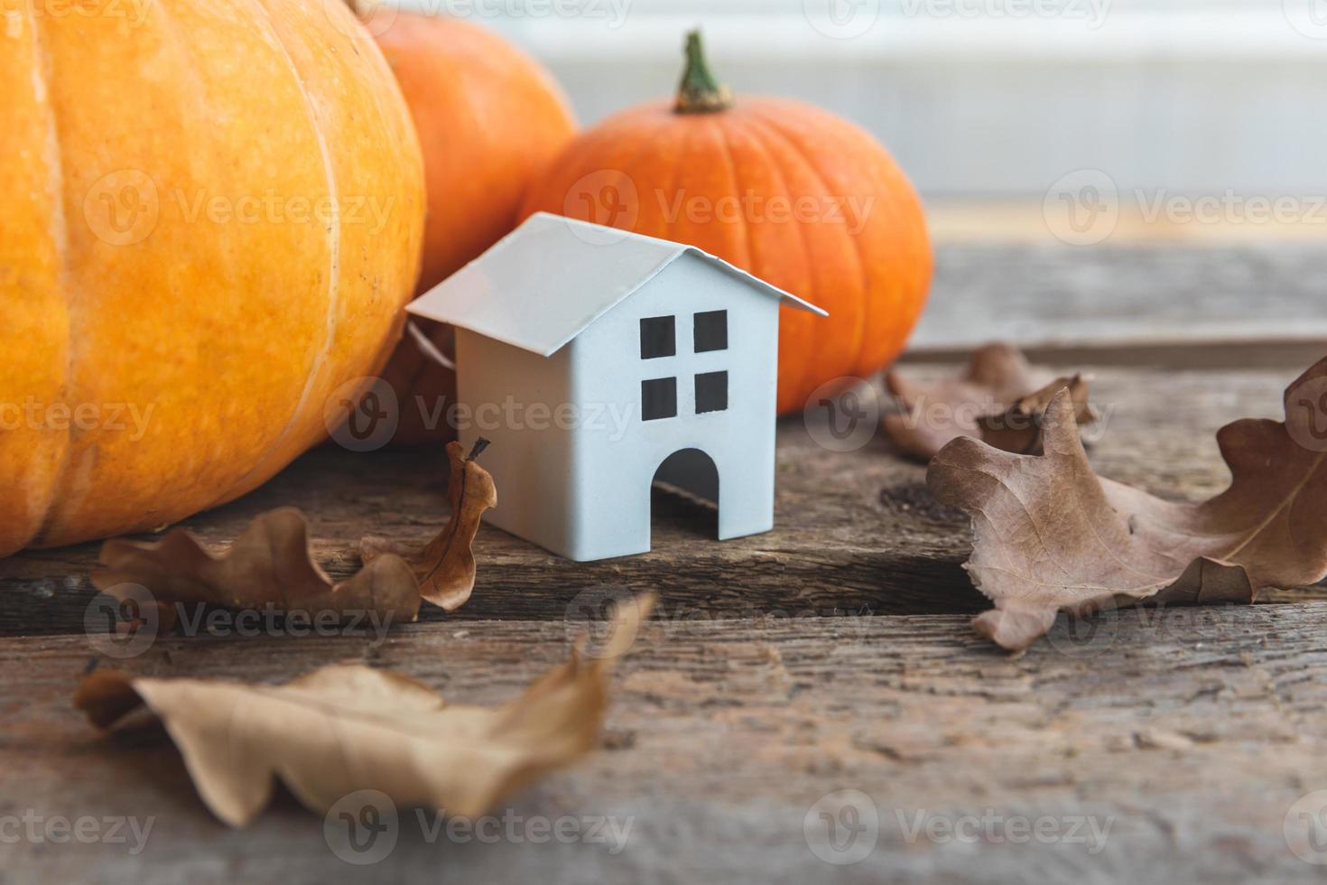 herbstlicher Hintergrund. Spielzeughaus und Kürbis auf Holzhintergrund. Thanksgiving-Banner kopieren Platz. Hygge-Stimmung, Wechsel der Jahreszeiten. hallo herbst mit familien-halloween-party. foto