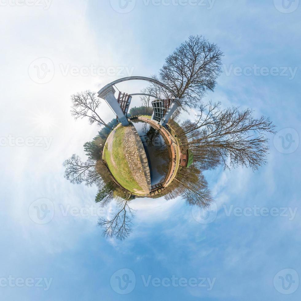 grüner kleiner winziger planet mit bäumen in der nähe der schleuse am fluss, weiße wolken und weicher blauer himmel des vergnügungsparks. 360-Grad-Sichtengel. Planet Erde. foto