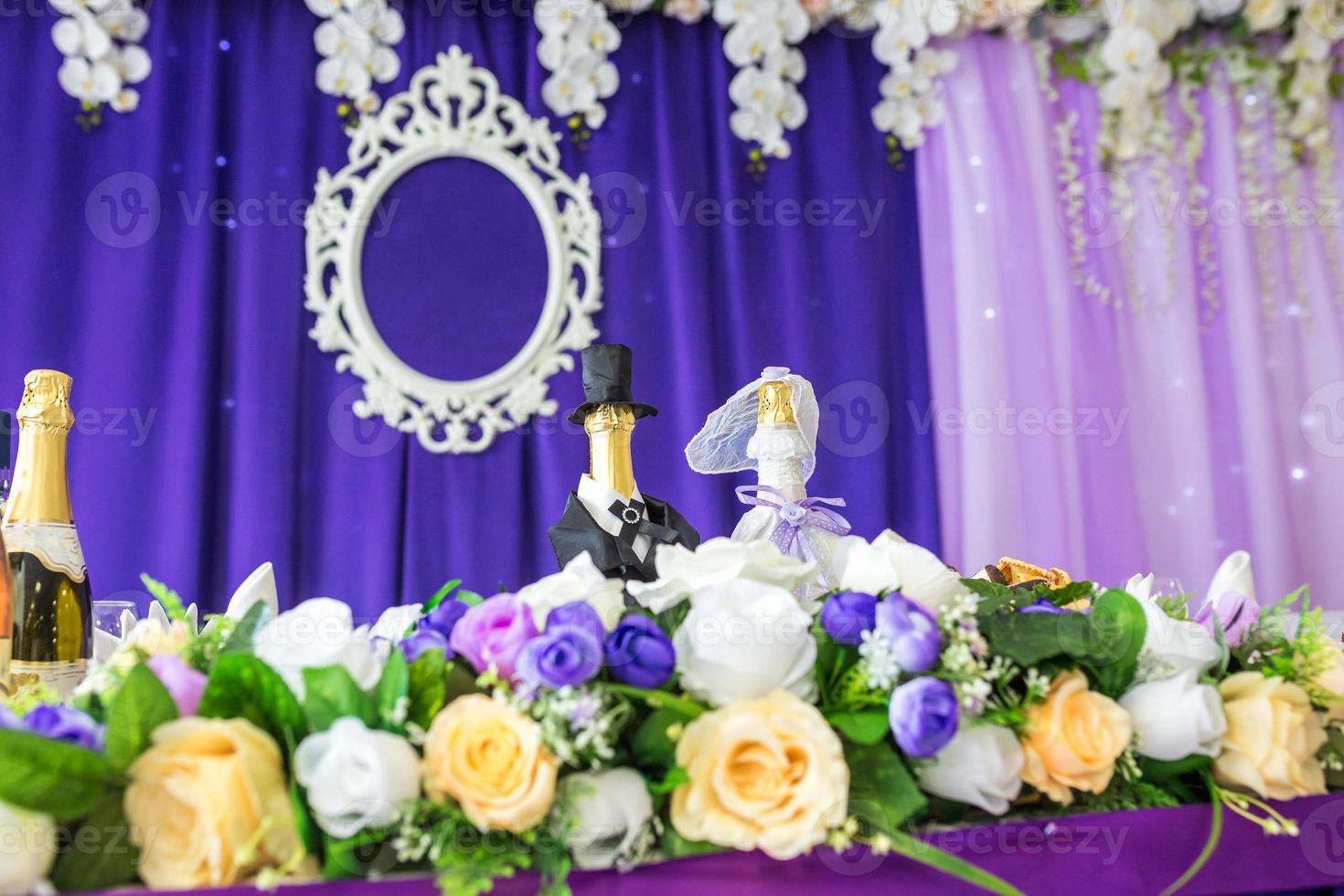 Schöne Blumen auf einem eleganten Esstisch am Hochzeitstag. Dekorationen, die auf dem festlich gedeckten Tisch in violettem Hintergrund serviert werden foto