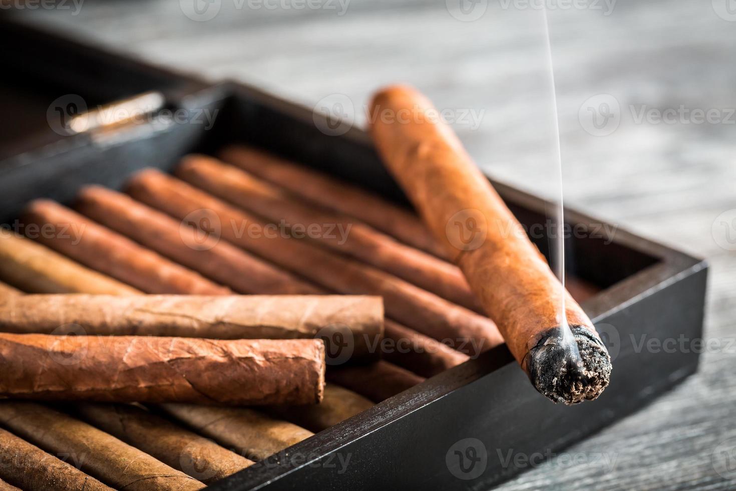 Rauch steigt von einer brennenden Zigarre auf foto