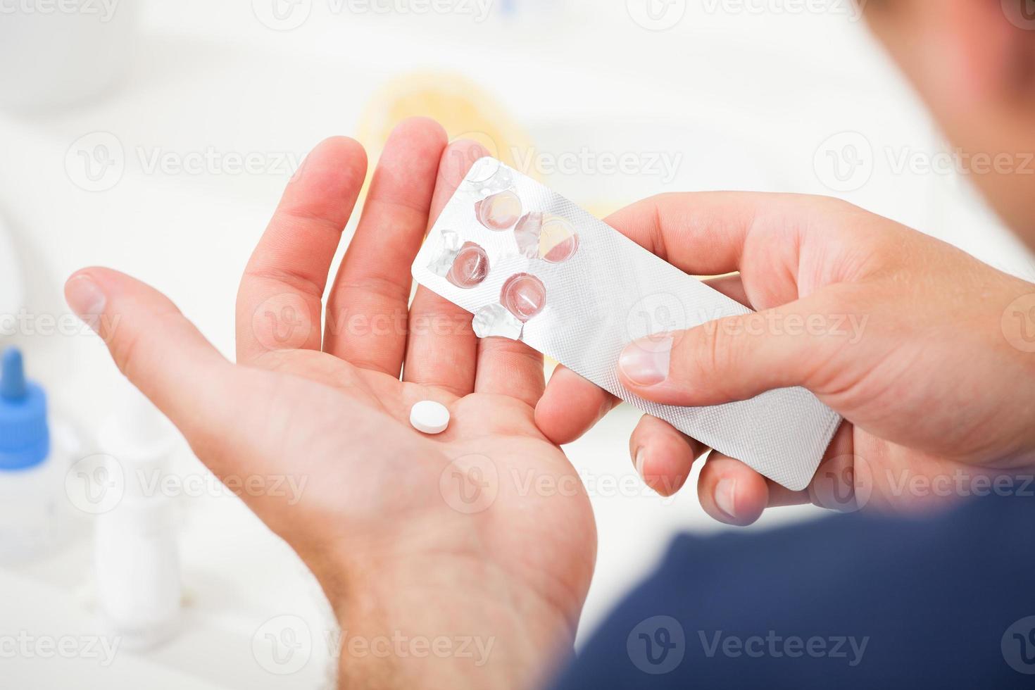 Mann nimmt Pille aus Blisterpackung heraus foto