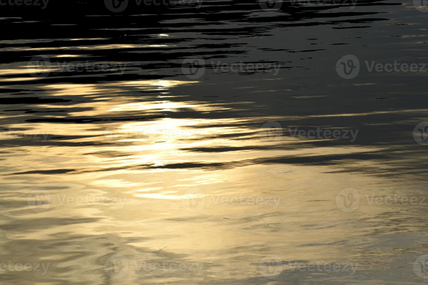 goldenes ozeanwasser, fotohintergrund. schönes sommermeer, sonnenuntergangszeit. natürlicher hintergrund der ozeanoberfläche. hintergrund für beschriftungen, karten, banner, design- und dekorelemente foto