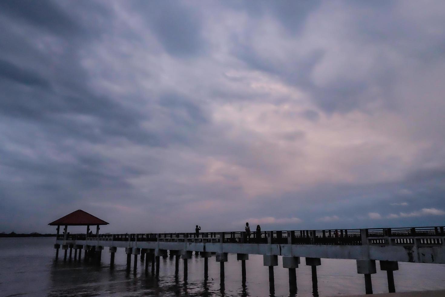 betonbrücke und pavillon auf dem ozean mit schönem sonnenunterganghimmel am bewölkten tag, thailand foto