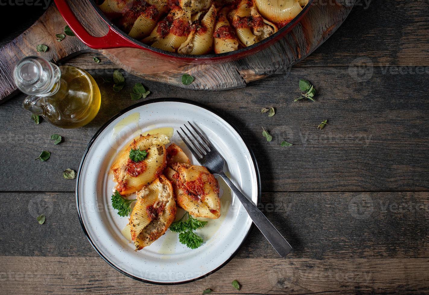 Manicotti-Nudelschalen mit Spinat, Ricotta, Mozzarella-Käse in Tomatensauce auf Teller in rustikaler Umgebung flach gelegt foto