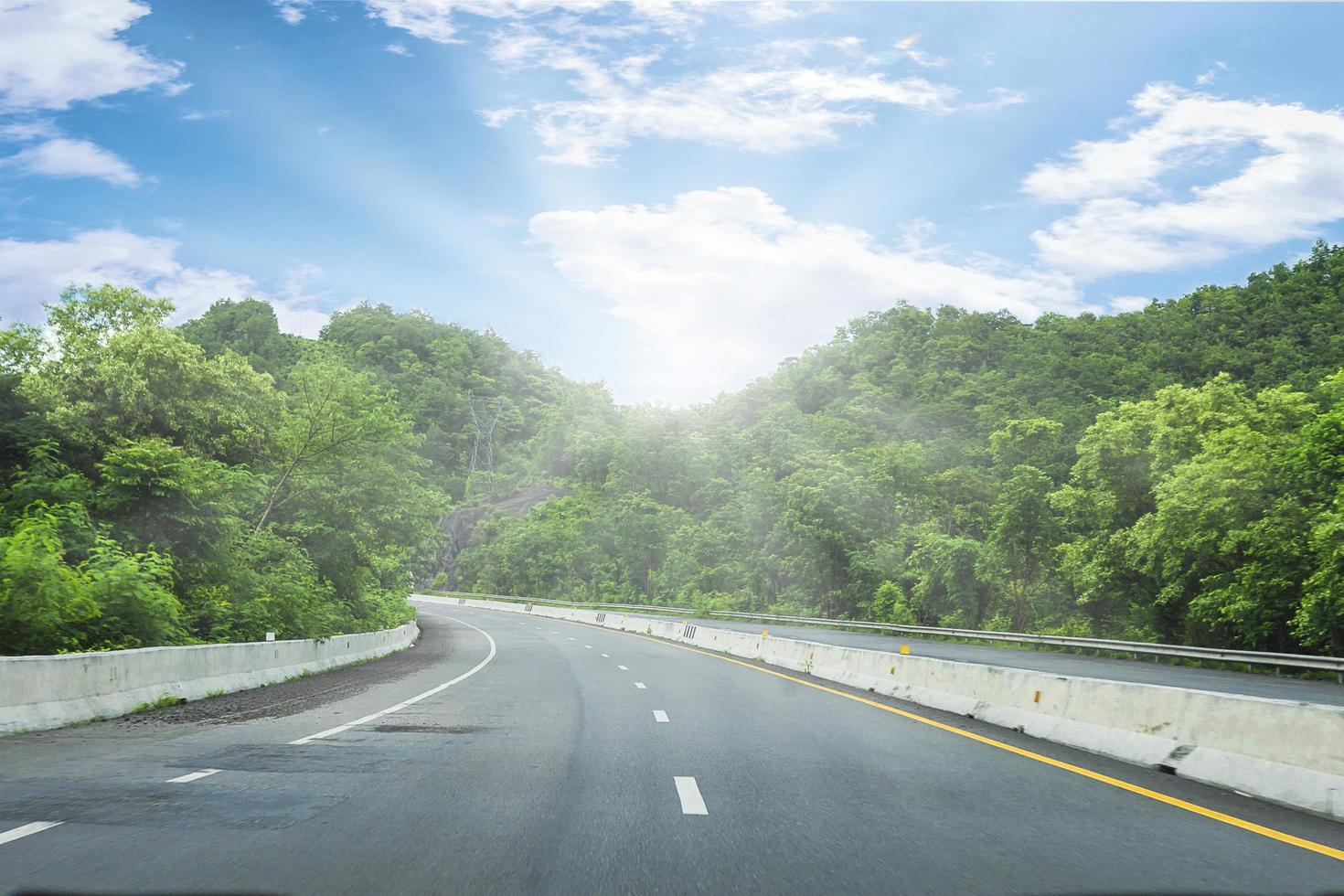 schöne autobahnstraße von thailand mit grünem berg und blauem himmelhintergrund foto